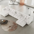 Modern white U-shaped sectional sofa in a minimalistic living room with a coffee table and rug.