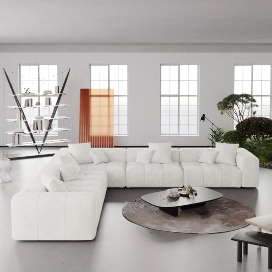 Modern living room with a large white V-shaped corner sectional sofa, coffee table, and decorative elements.