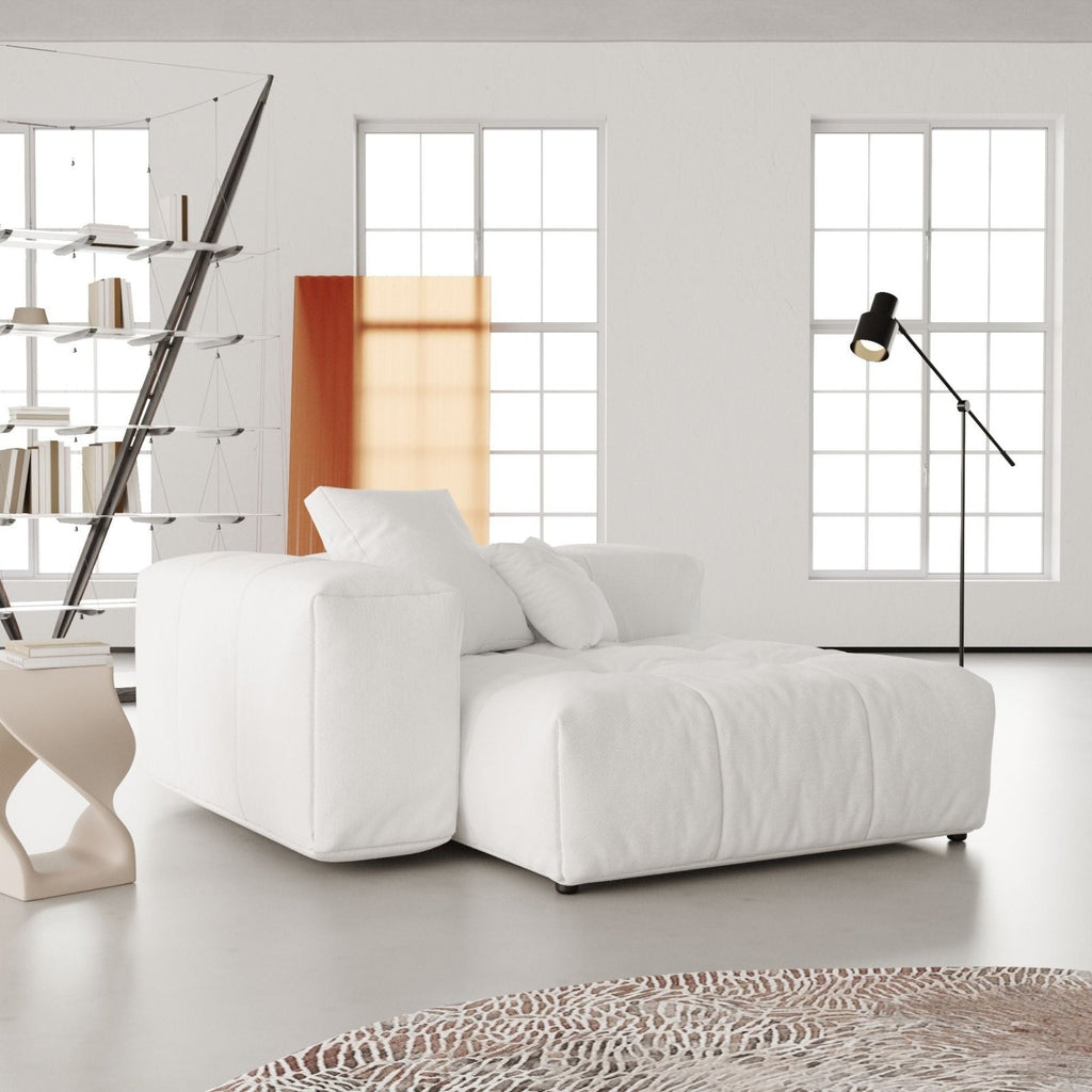 White deep end chair in a modern living room with large windows and minimal decor.