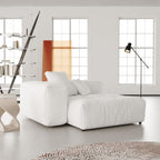 White deep end chair in a modern living room with large windows and minimal decor.