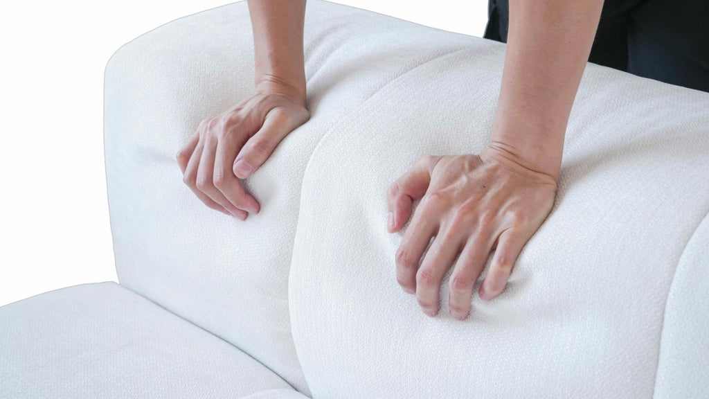 A close-up of a person touching the back of a Strata Modular sofa, showcasing its design and texture.