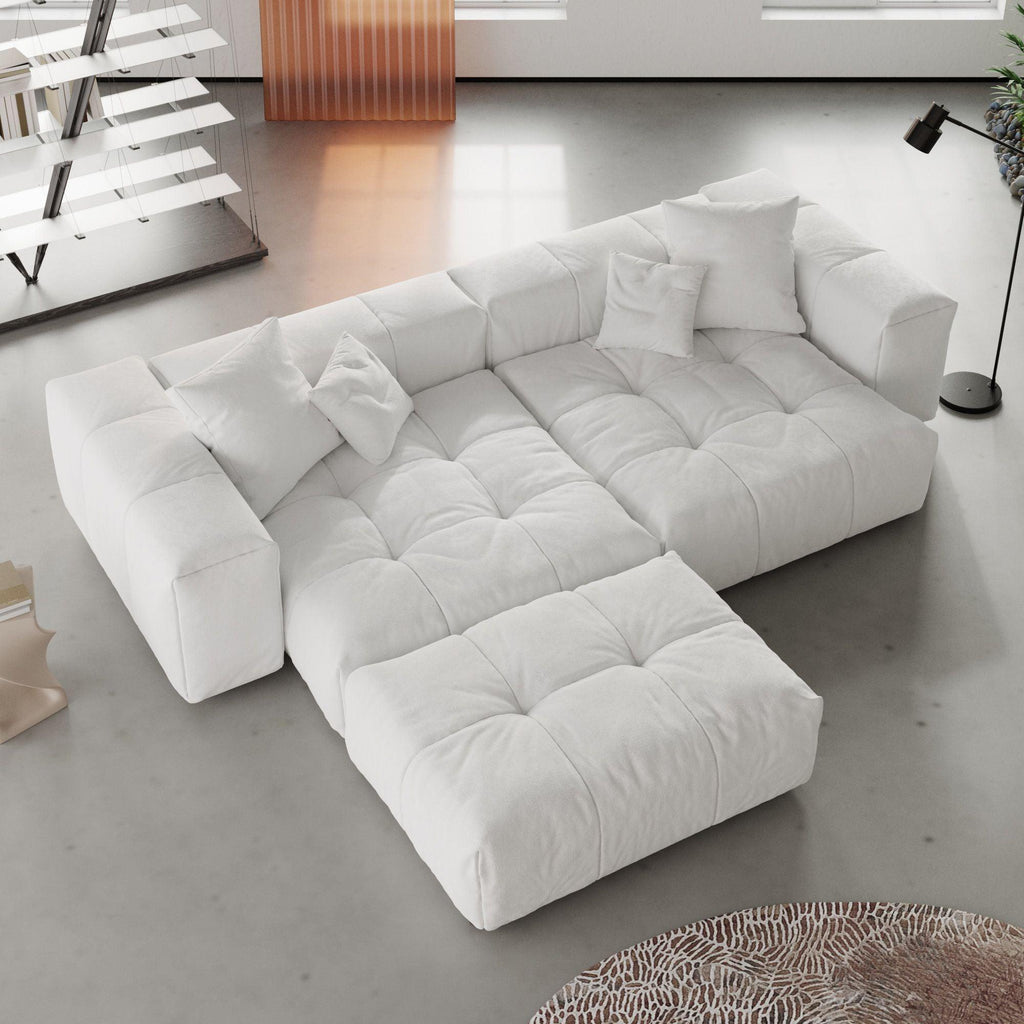 White loveseat sofa with ottoman in a modern living room with a rug and lamp.