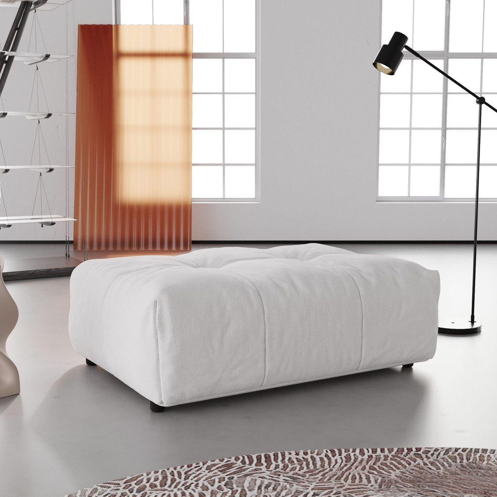 A white linen ottoman in a modern living room setting, with a low-profile and cushioned top.