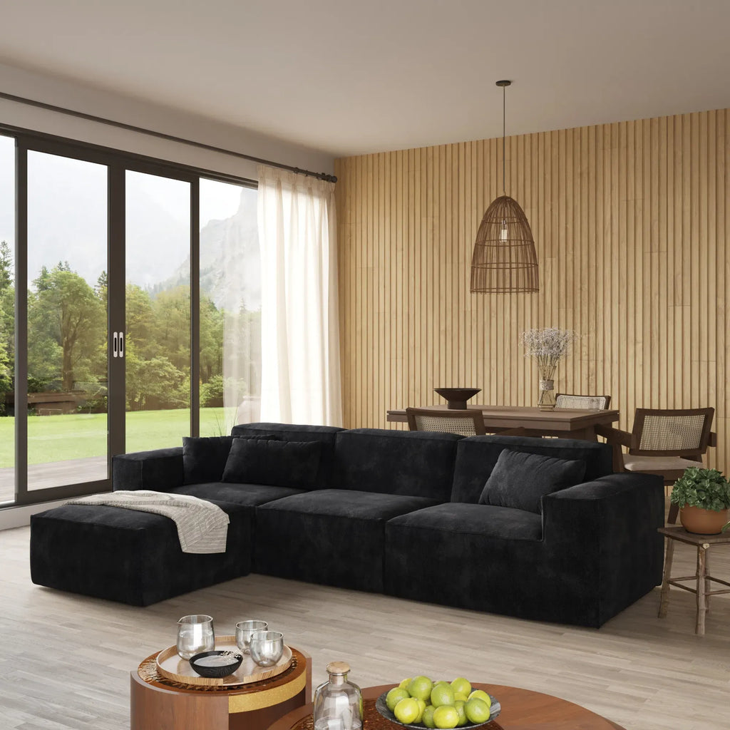 Modern living room with a black sectional sofa, coffee table, and decorative items.