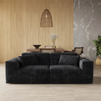 Black sofa in a modern living room with wooden floor and decorative elements.