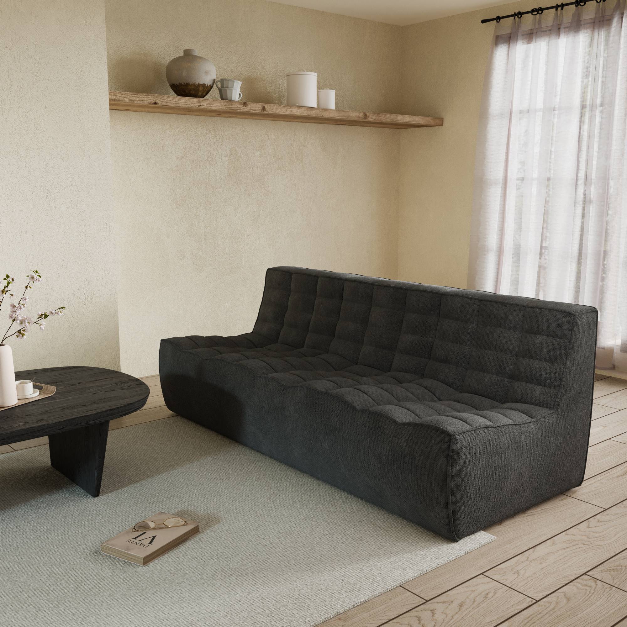A black chenille waffle floor 3-seater sofa with a minimalist design, placed in a room with a window, curtains, and a small round table with an object on it.