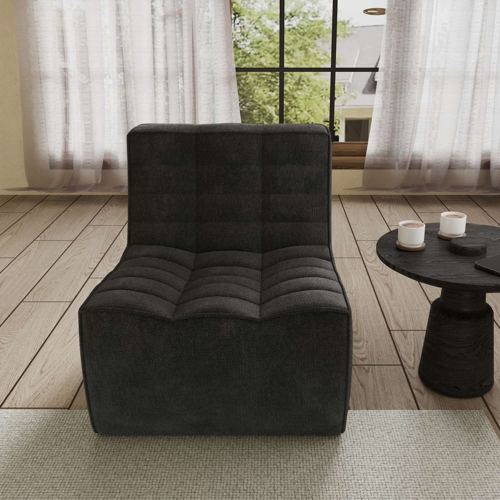 A black chenille accent chair with a minimalist design, positioned in a room with a window, curtains, and a small round side table.