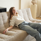 Person sitting on a beige waffle style floor 3-seater sofa