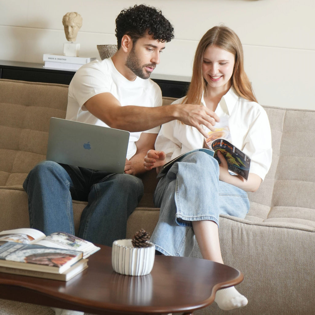 A couple sitting on a beige waffle style 3 s-eater sofa reading magazine