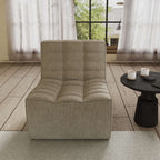 A khaki chenille accent chair with a minimalist design, positioned in a room with a window, curtains, and a small round side table.