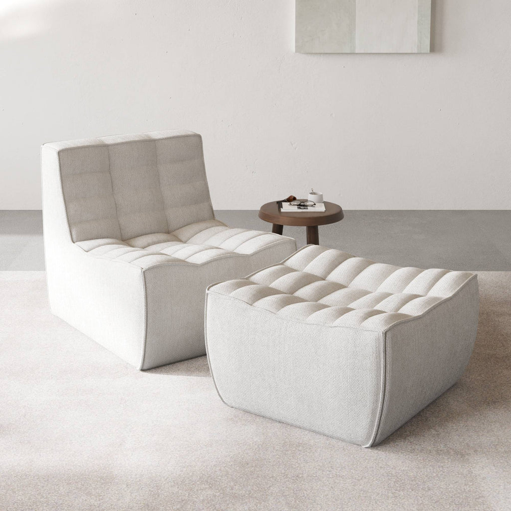 A light gray chenille accent chair and ottoman with a minimalist design in a day light