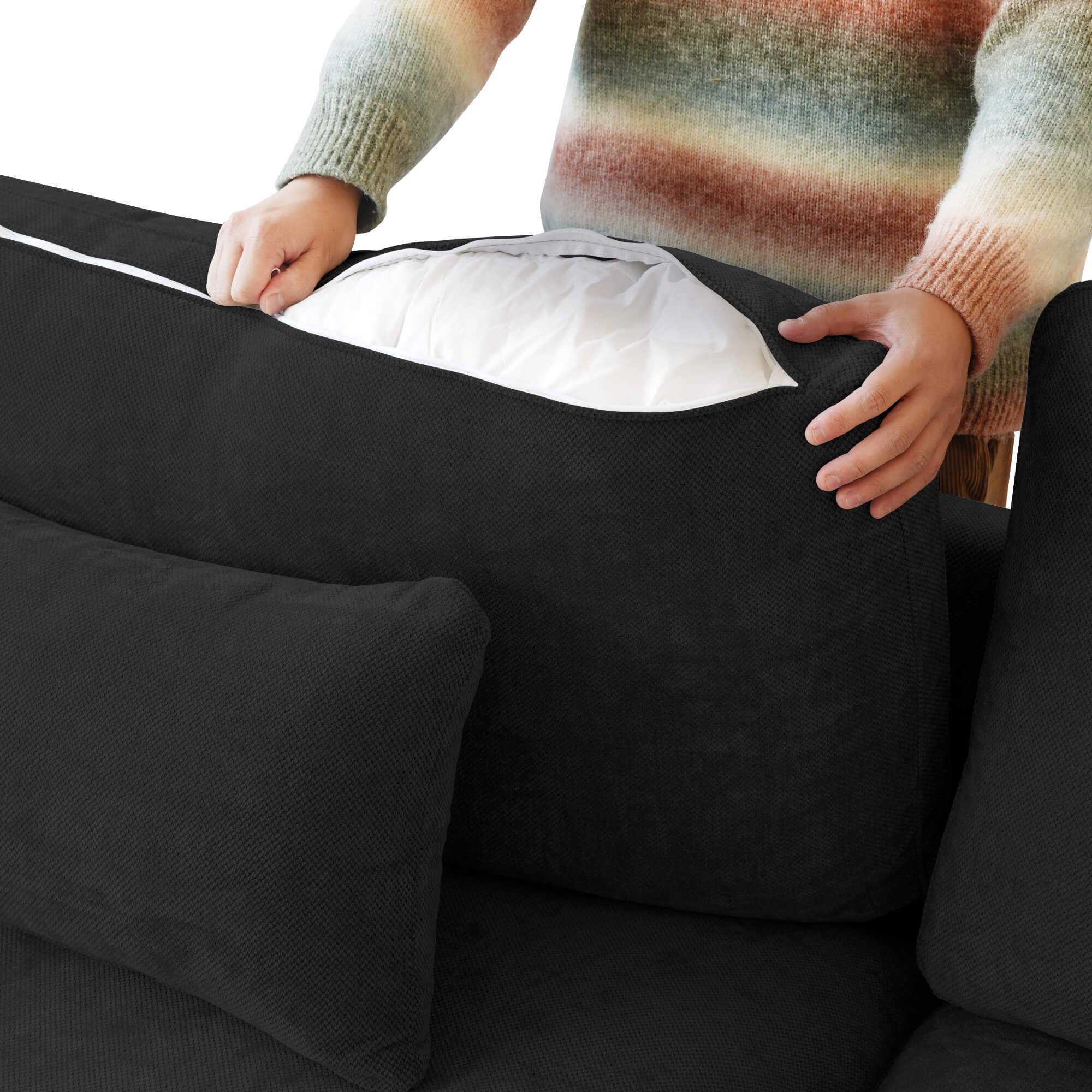 Person unzipping a black linen over of a backrest cushion of a black couch