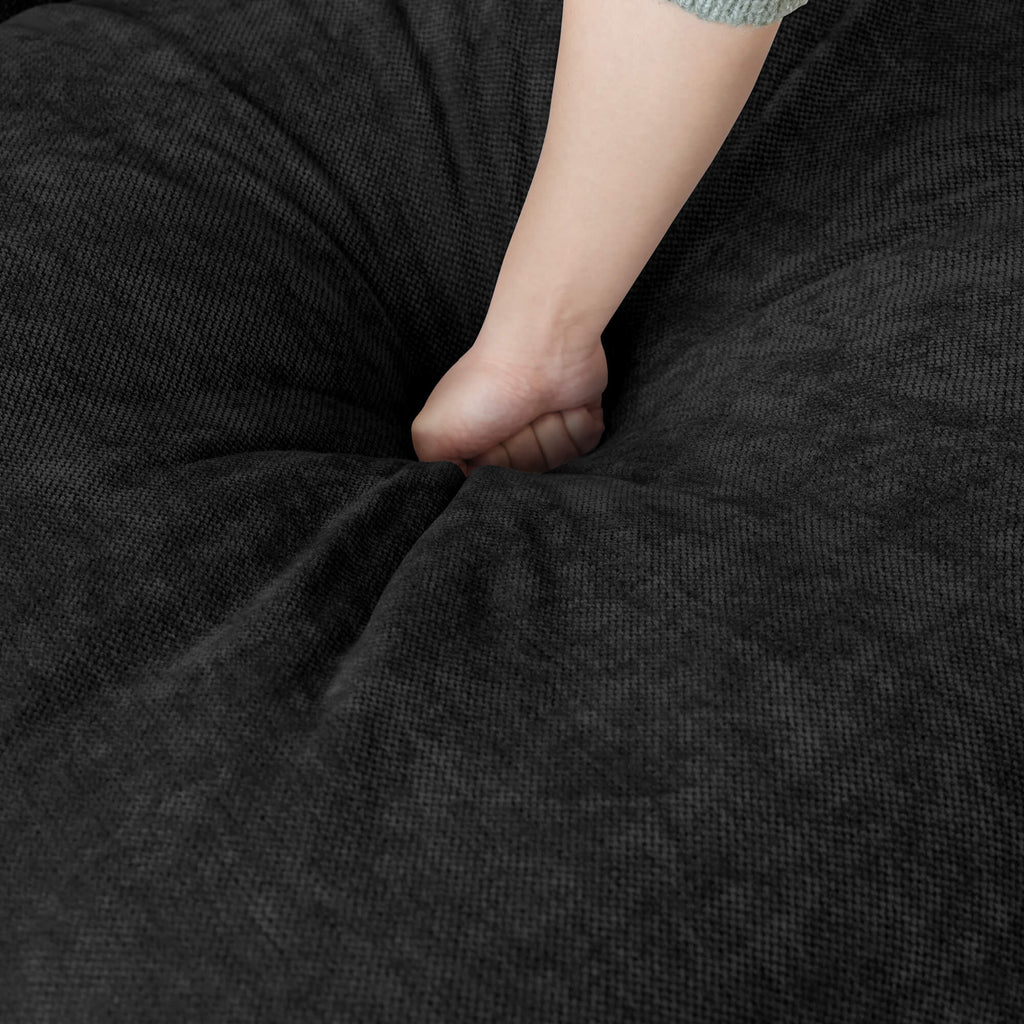 Person pressing on a seat cushion of a black couch