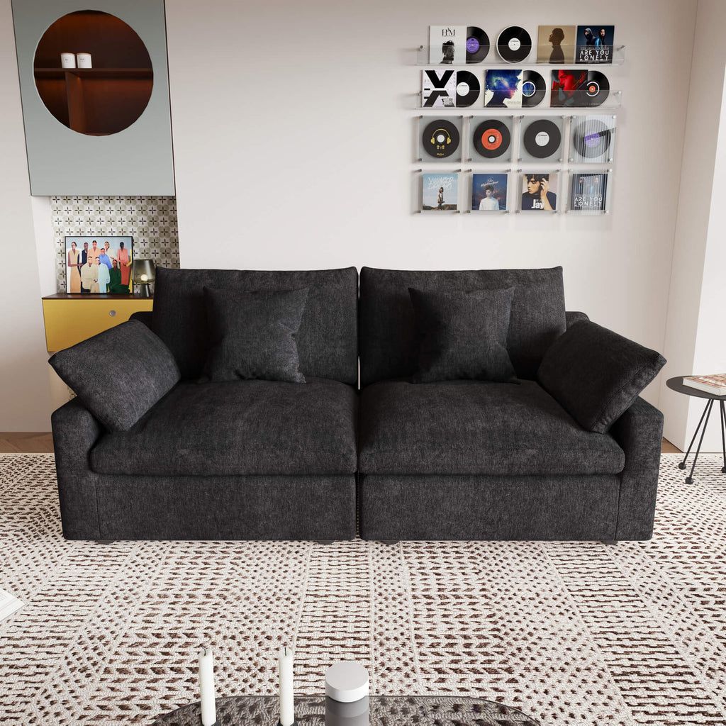 A black loveseat sofa, featuring a minimalist design with removable cushions, placed in a room with modern decor.