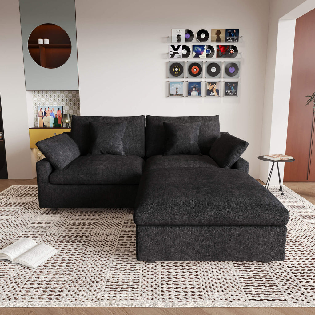 A black linen loveseat with ottoman, featuring a washable cloud design, placed on a patterned rug in a room with a record collection on the wall.