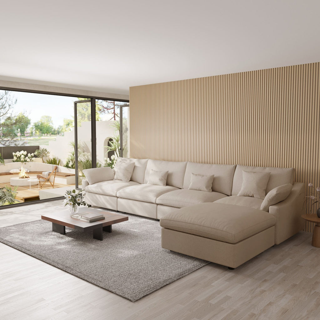 Khaki 5-seat sectional sofa with ottoman in a modern living room with large windows and a striped wall.