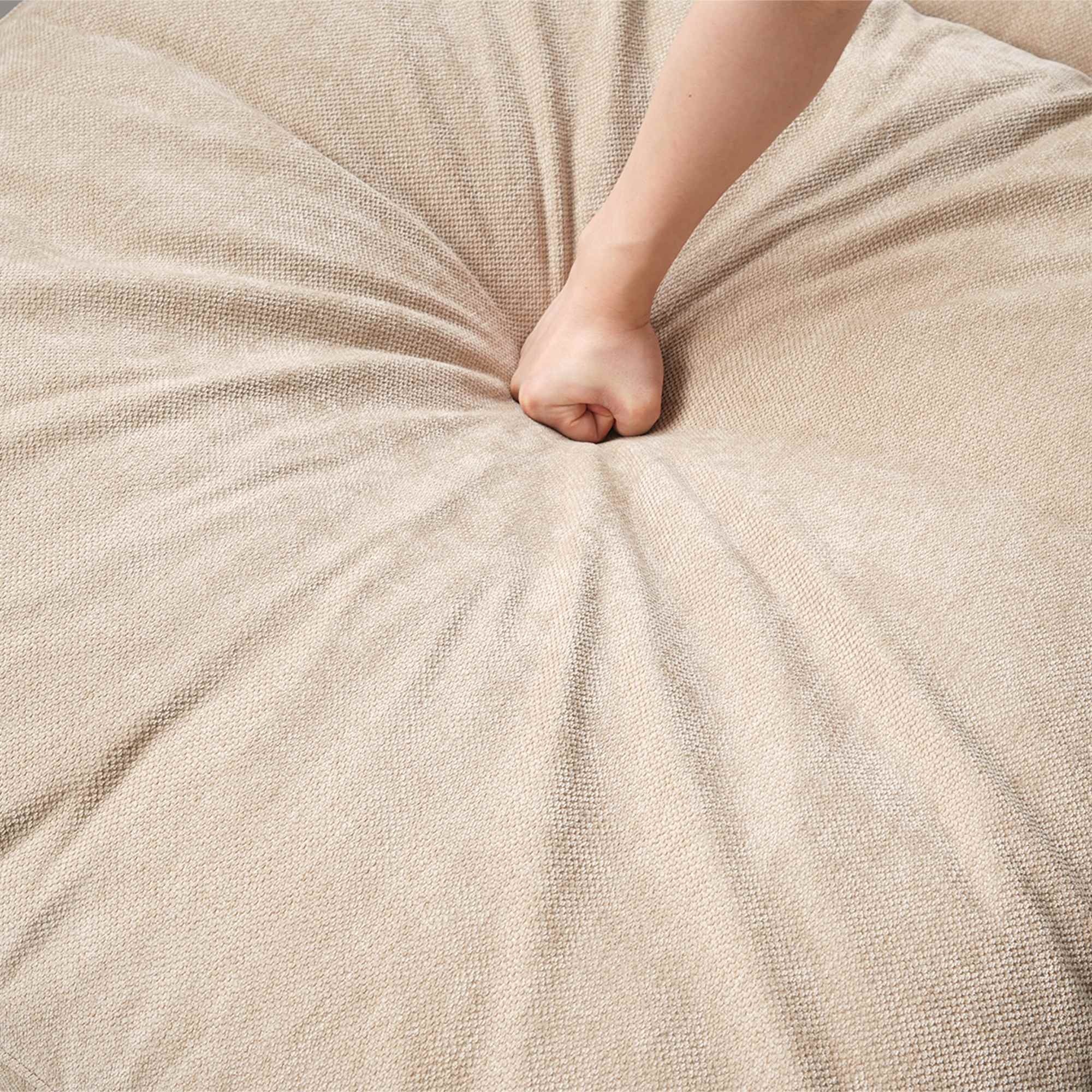 Person pressing on a linen khaki seat cushion
