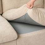 Person adjusting a khaki seat cushion over a sofa section.