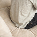 Person wearing a gray sweatshirt sitting on a beige couch