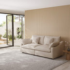 Khaki loveseat sofa in a modern living room with a striped wall and glass door.