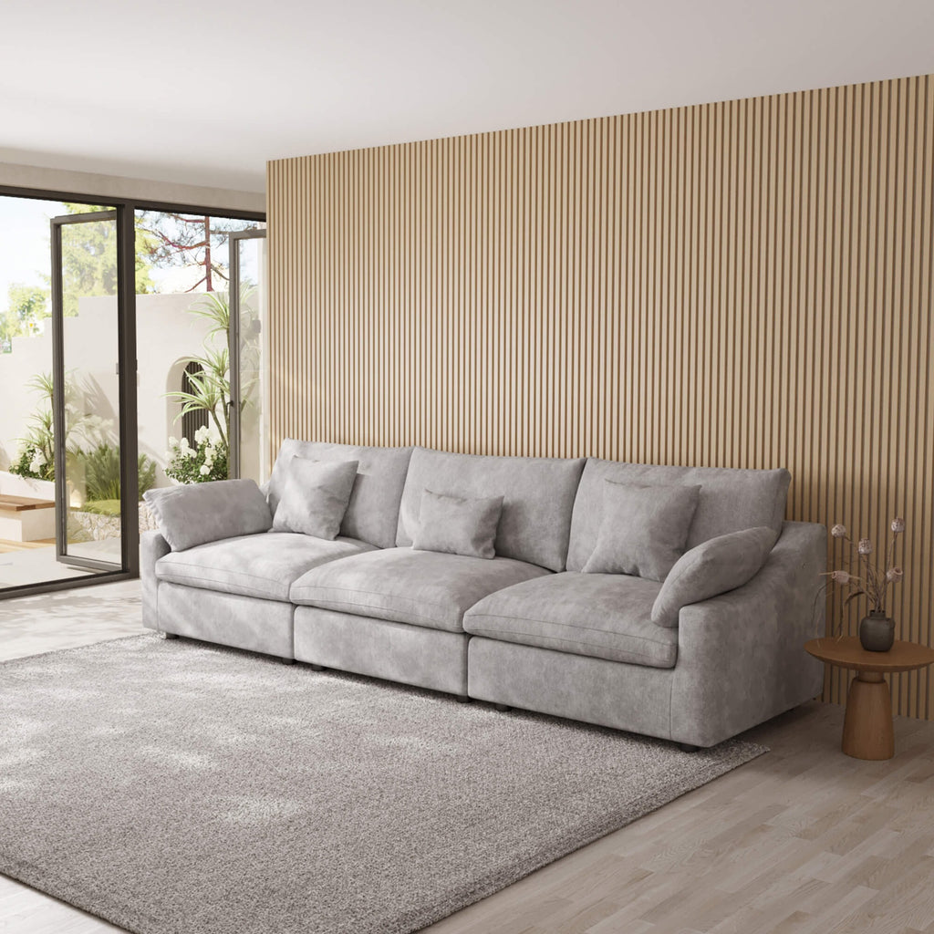 Light gray 3-seater couch in a modern living room with a wooden wall and large windows.