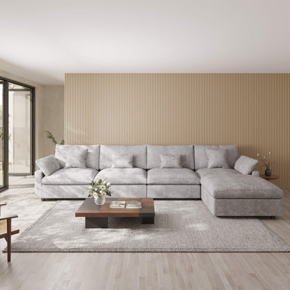 Light gray 5-seat sectional sofa with ottoman in a modern living room with a wooden coffee table and decorative elements.