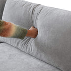 Person pressing on a backrest cushion of a gray linen couch