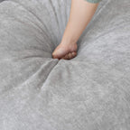 Person pressing on a seat cushion of a gray couch