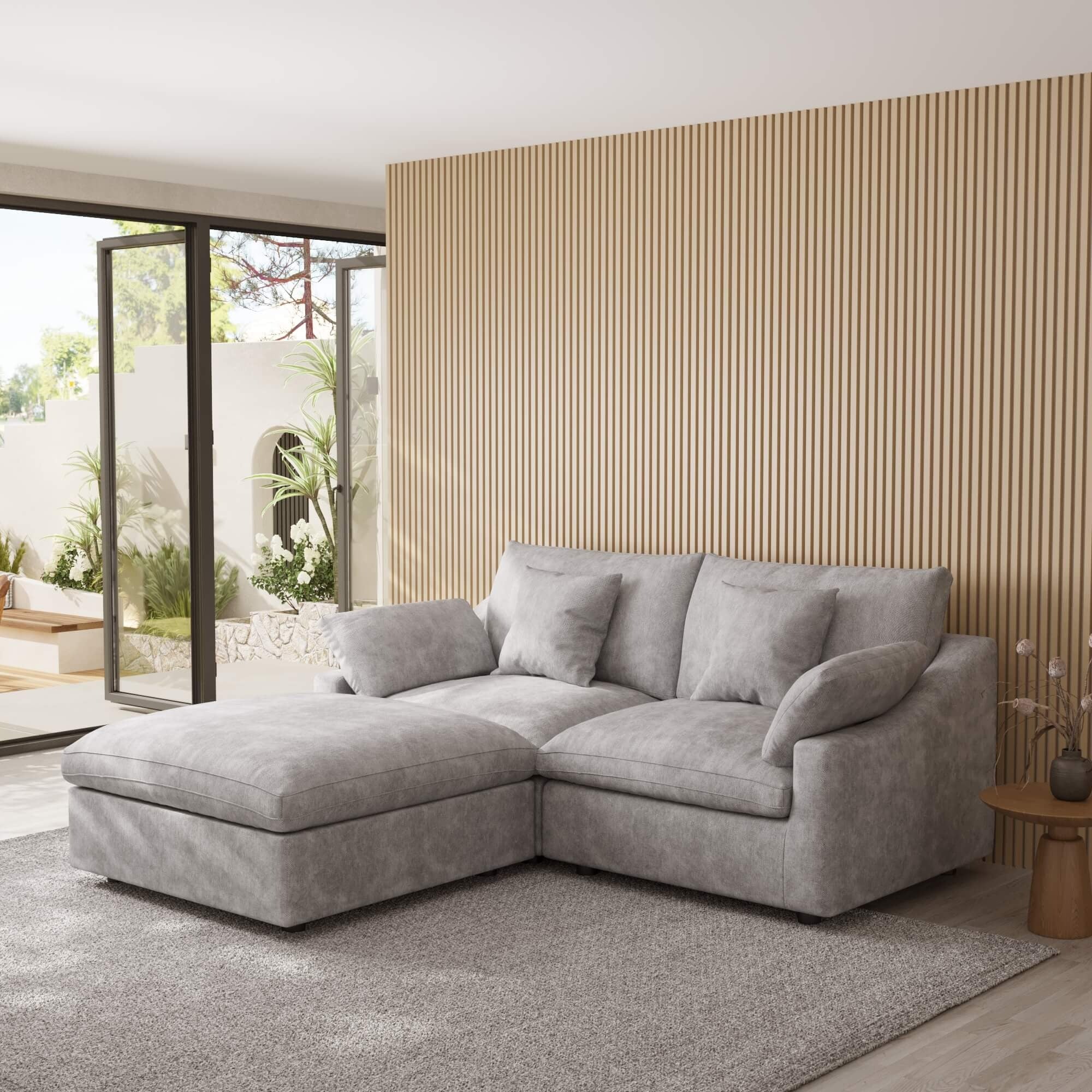 Light gray sectional chaise lounge sofa in a modern living room with a striped wall and patio door.