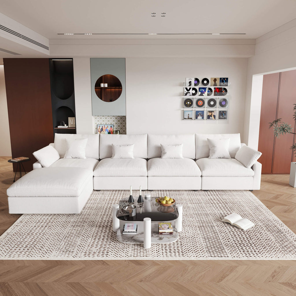 A large, white washable cloud sectional 5-seat sofa with removable cushions and an ottoman, placed in a living room setting.