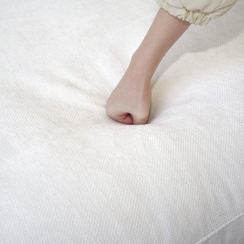 Person pressing on a seat cushion of a white sofa