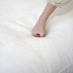 Person pressing on a seat cushion of a white sofa