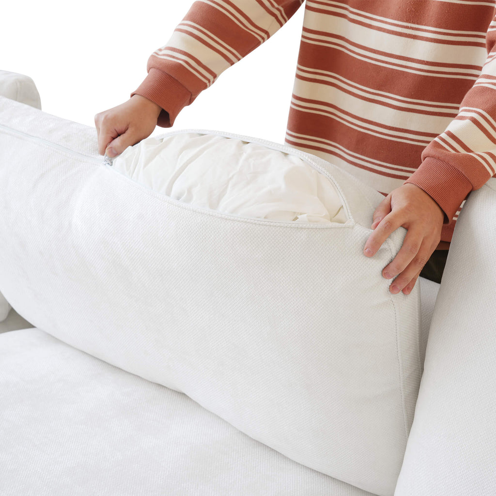 Person unzipping a backrest cushion cover of a white sofa