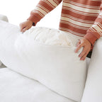 Person unzipping a backrest cushion cover of a white sofa