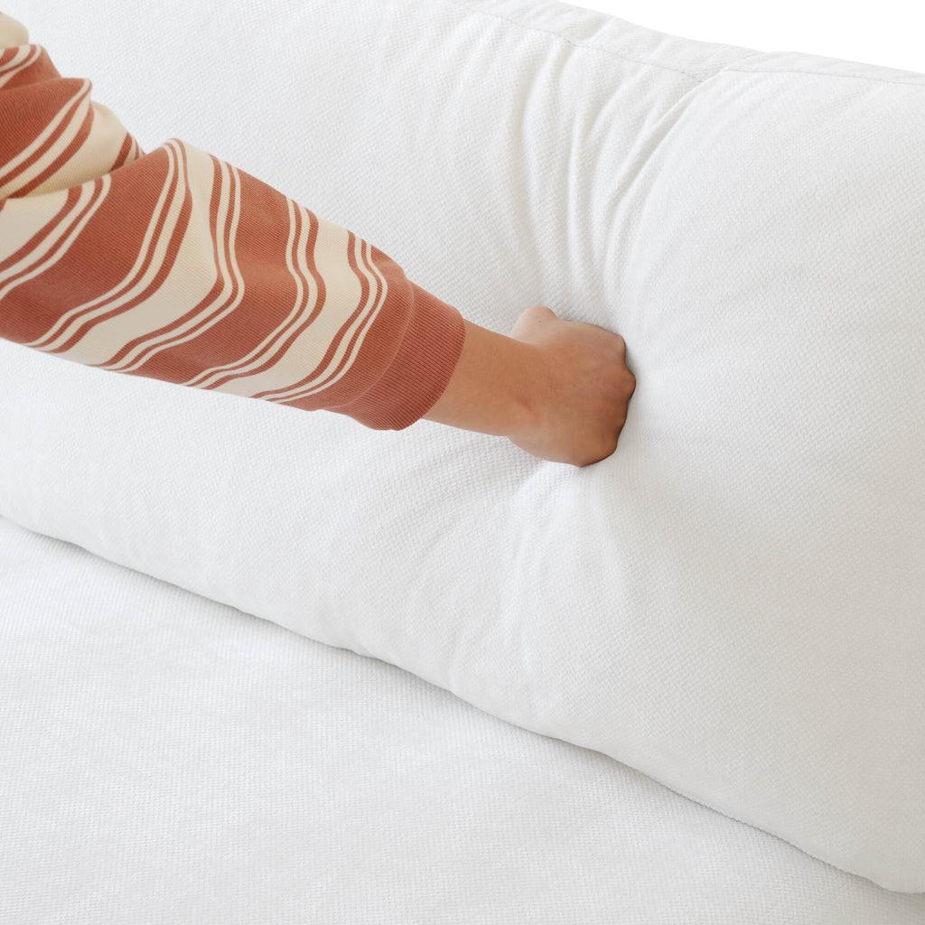 Person pressing on a backrest cushion of a white sofa
