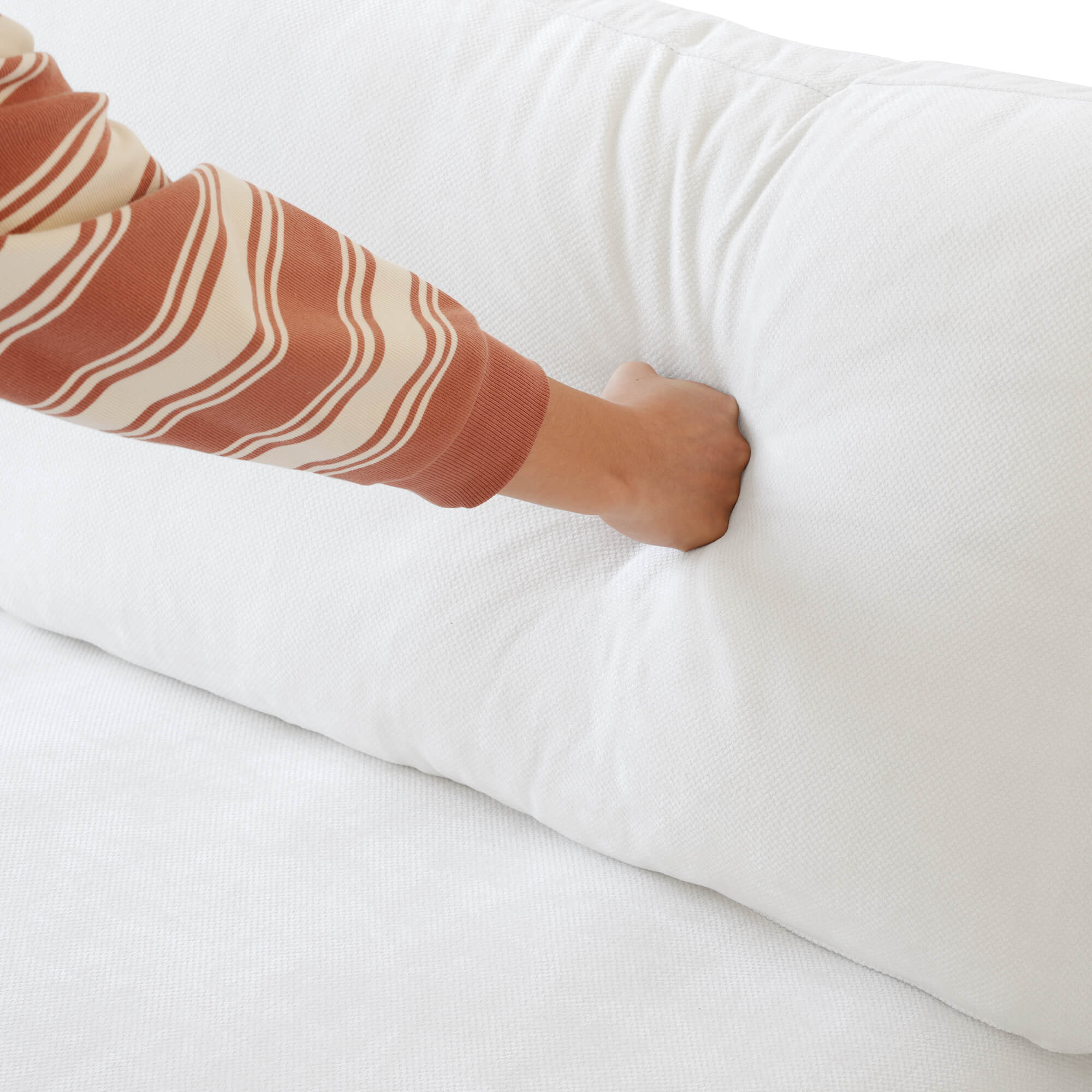 Person pressing on a backrest cushion of a white sofa