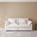 White loveseat sofa with decorative pillows against a beige paneled wall.