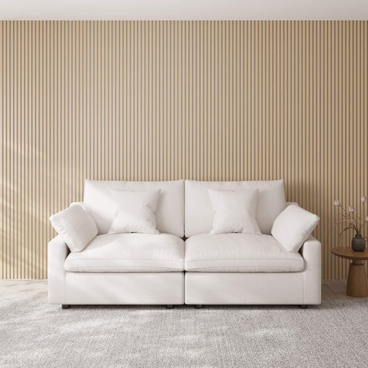 White loveseat sofa with decorative pillows against a beige paneled wall.
