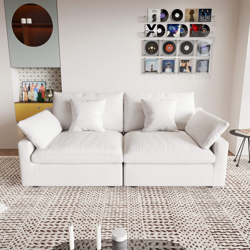 A white loveseat sofa, featuring a minimalist design with removable cushions, placed in a room with modern decor.