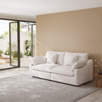White loveseat sofa in a modern living room with a striped wall and patio doors.