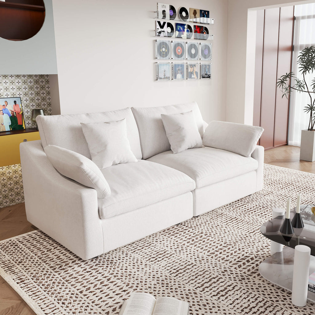 A white loveseat sofa, featuring a minimalist design with removable cushions, placed in a room with modern decor.