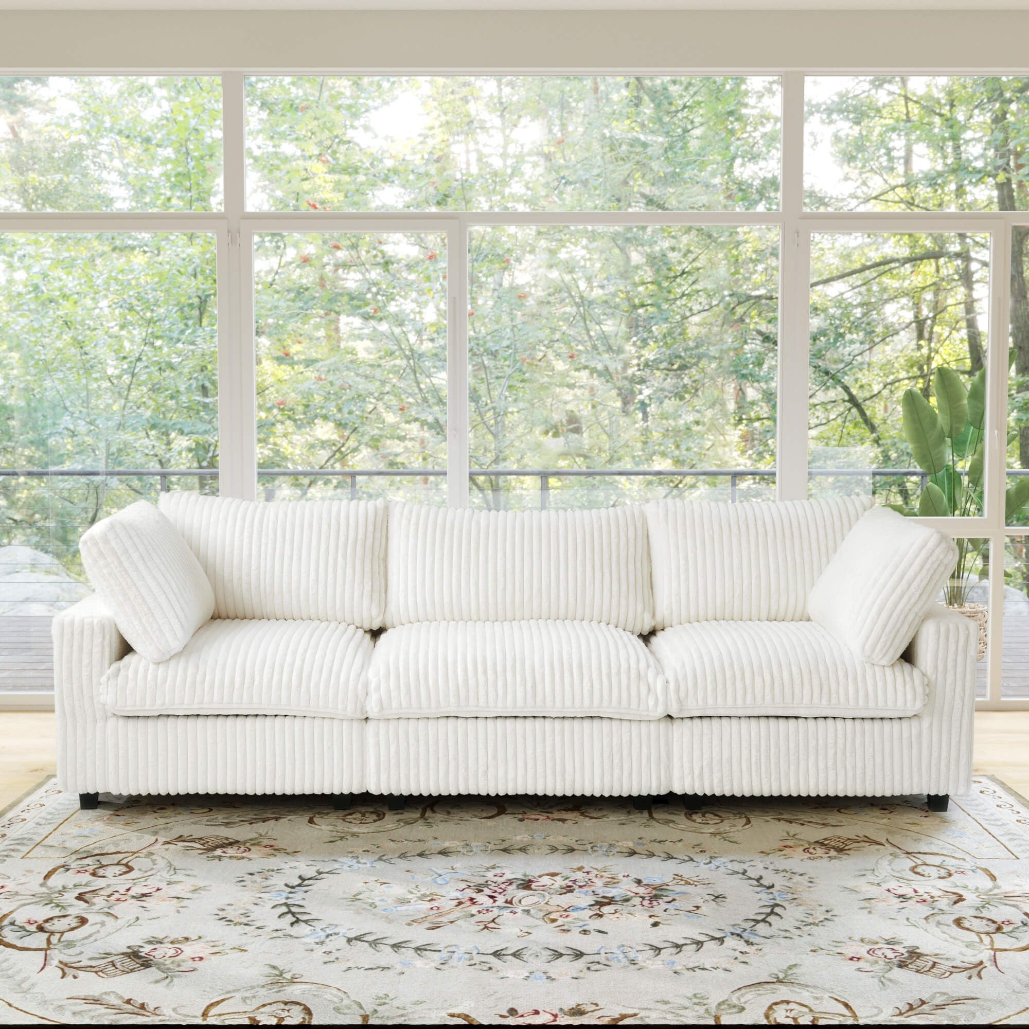 Beige 3-seat sofa in a room with large windows and a floral rug