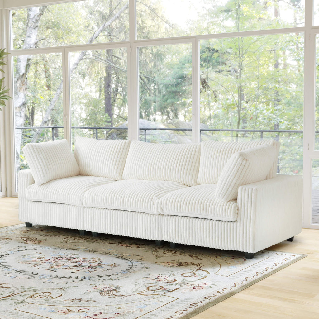 Beige 3-seat sofa in a room with large windows and a decorative rug.