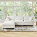 Beige L-shaped sectional sofa in a room with large windows and a view of trees.