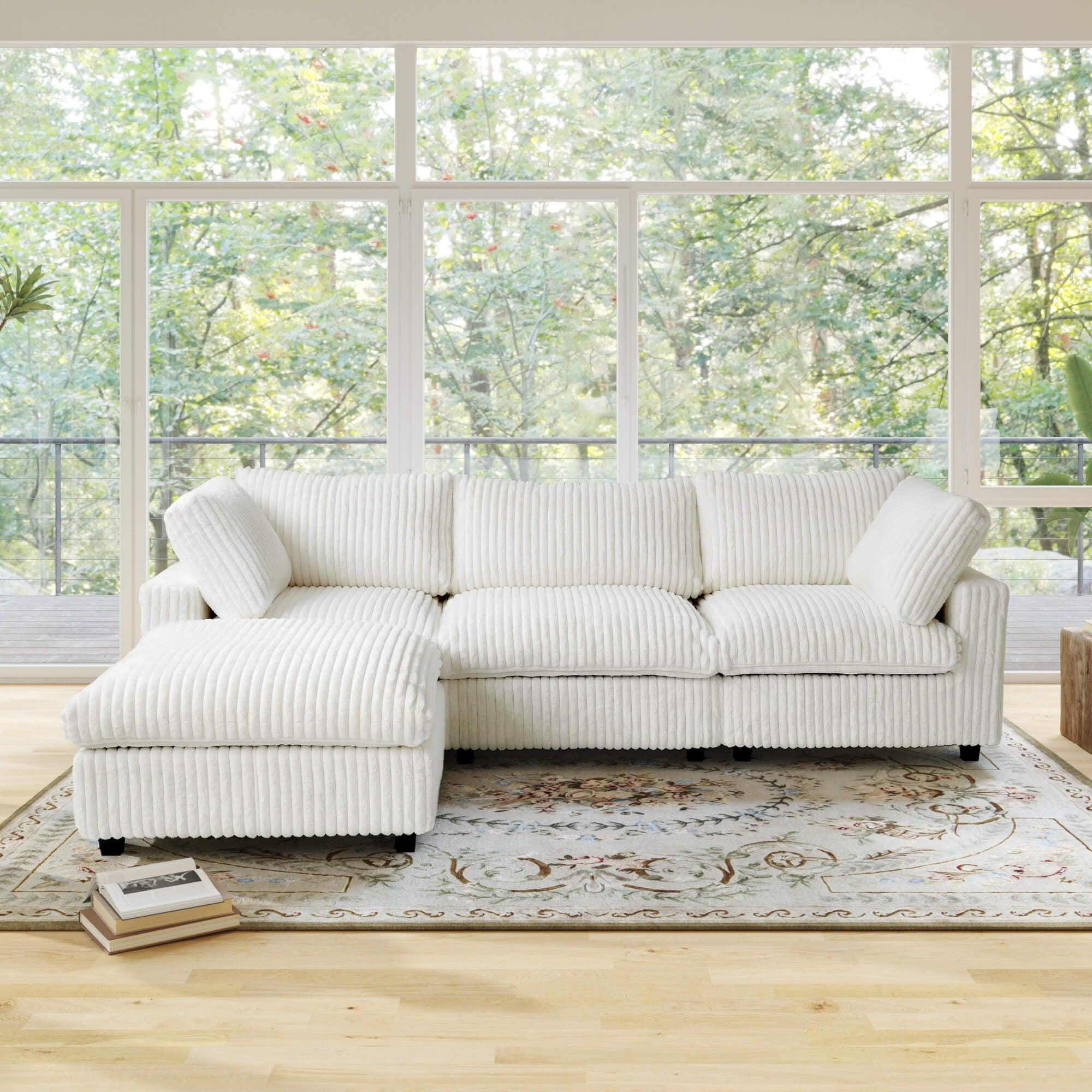 Beige L-shaped sectional sofa in a room with large windows and a view of trees.
