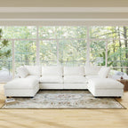 Beige U-shaped sectional sofa in a room with large windows and a view of trees.