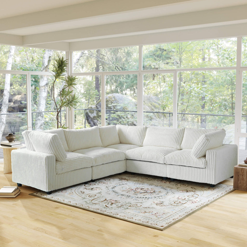 Beige corner sectional sofa in a room with large windows and a rug.