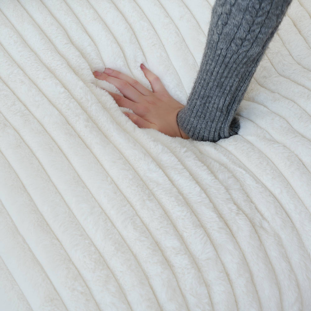 Close-up of a hand pressing on a seat cushion of a beige faux rabbit fur sofa