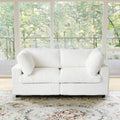 White faux rabbit fur sofa in a room with large windows showing greenery outside.