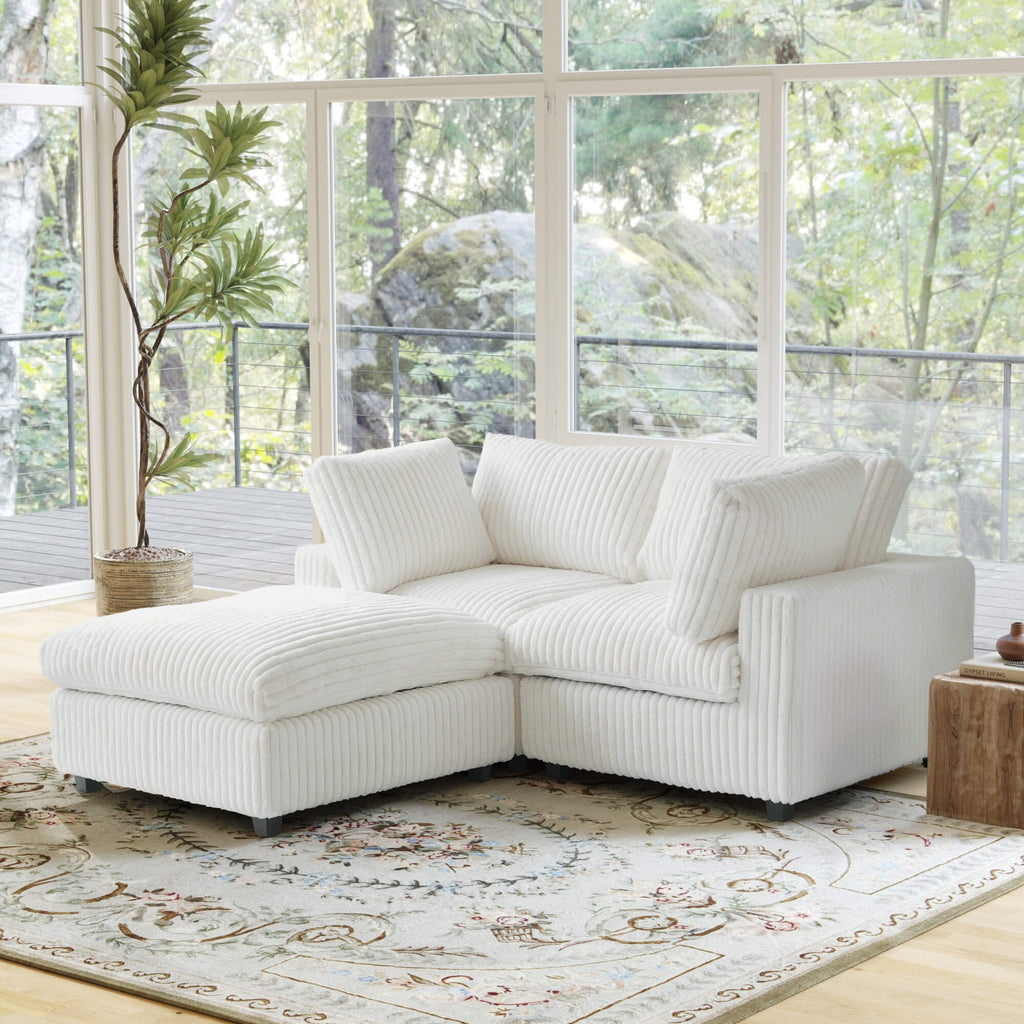 Beige faux rabbit fur sectional loveseat sofa with ottoman in a living room with large windows and a decorative rug.